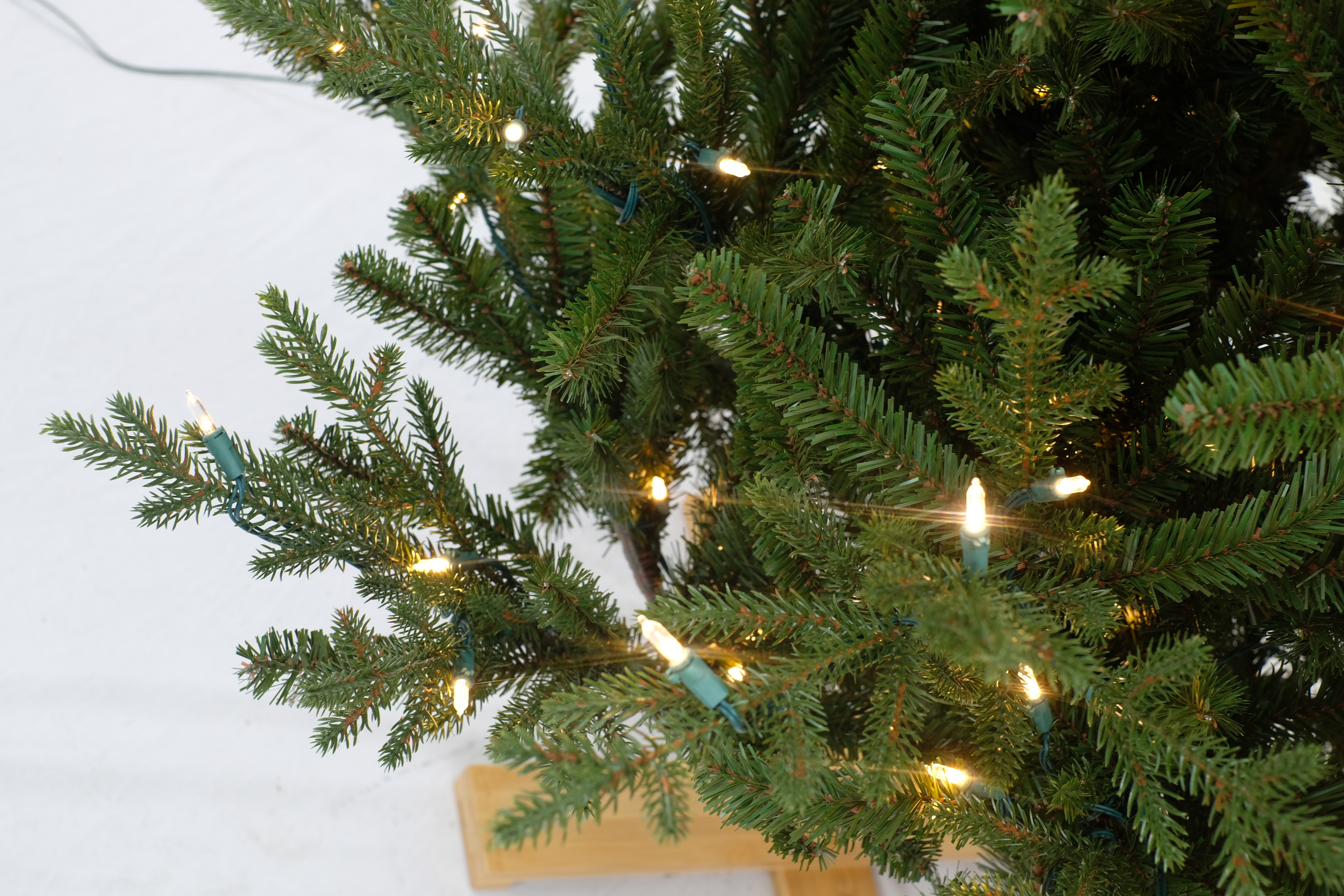 Kunstkerstboom - Levensechte dennenlook, subtiel verlicht, met houten voet | 213 cm - 450 Lampjes