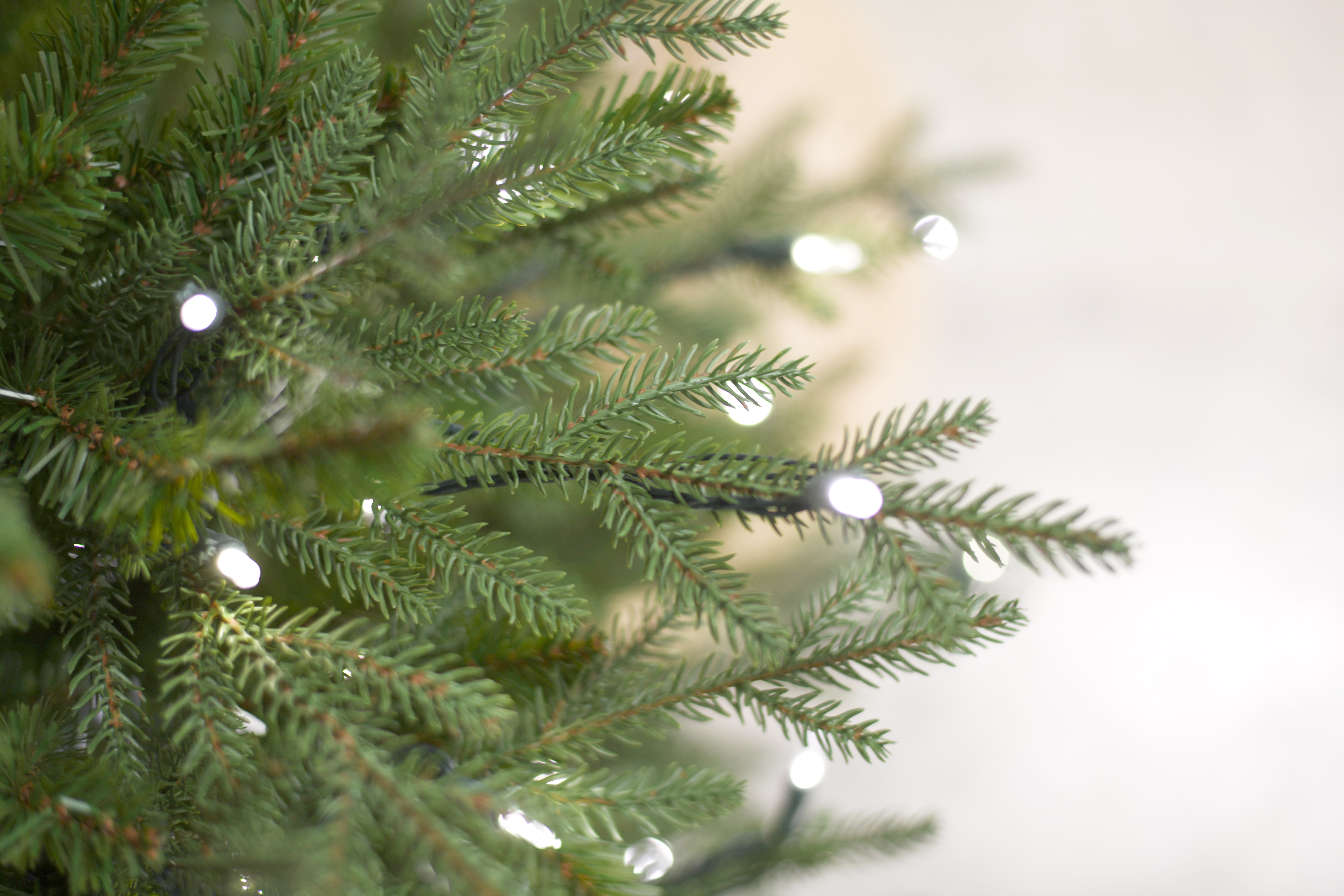 Kunstkerstboom - Levensechte dennenlook, subtiel verlicht, met houten voet | 213 cm - 450 Lampjes
