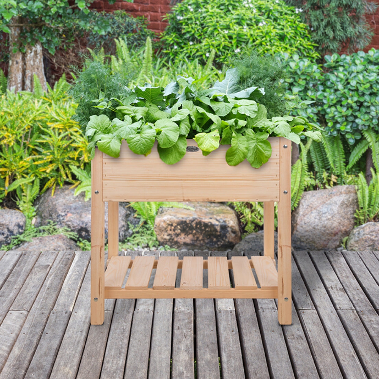 Een houten verhoogde plantenbak met een roosterbodem en een opbergplank eronder, gevuld met groene bladgroenten en kruiden.