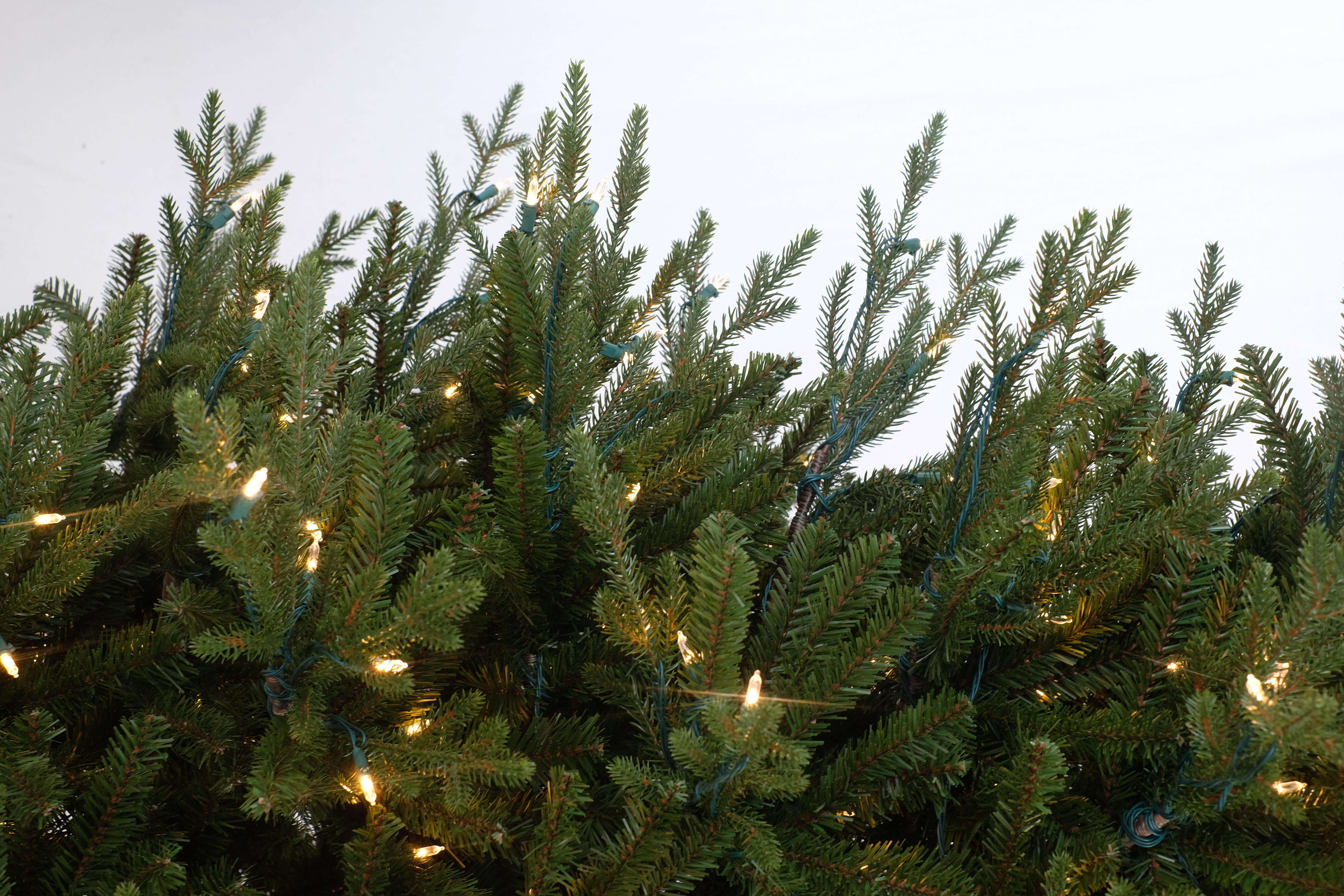 Kunstkerstboom - Levensechte dennenlook, subtiel verlicht, met houten voet | 213 cm - 450 Lampjes